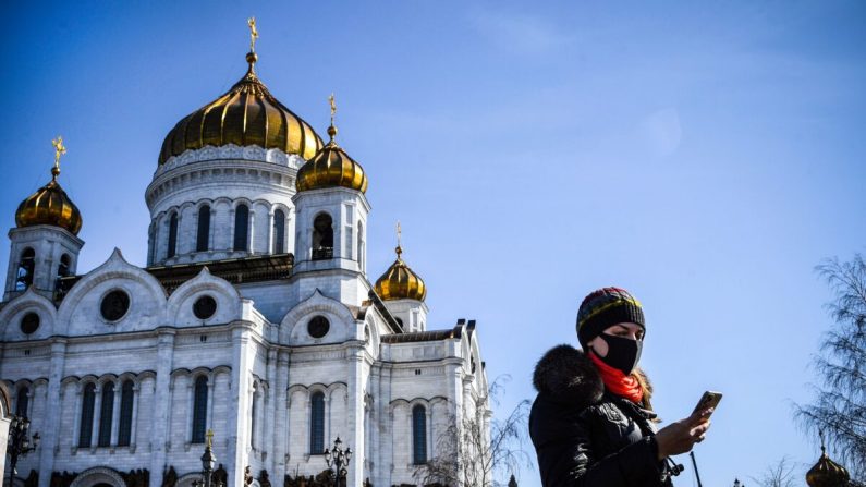 Une femme portant un masque facial, au milieu des inquiétudes concernant la propagation du virus du PCC, passe devant la cathédrale du Christ-Sauveur dans le centre de Moscou le 26 mars 2020. (ALEXANDER NEMENOV/AFP via Getty Images)