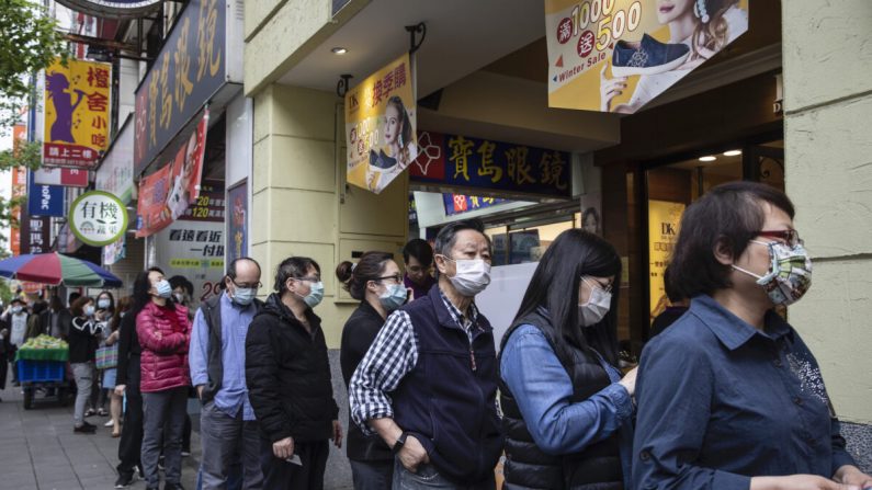 Des personnes font la queue dans une pharmacie pour récupérer des masques pré-commandés en ligne, à Taipei, Taïwan, le 18 mars 2020. (Paula Bronstein/Getty Images )