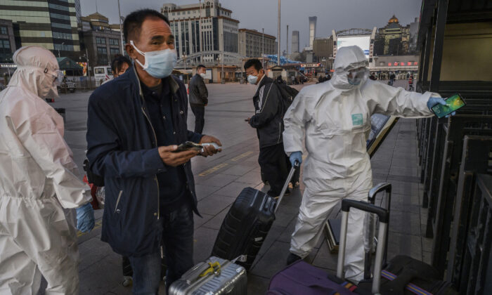 Les gens portant des masques et des vêtements de protection arrivent à la gare de Pékin, le 13 mars 2020. (Kevin Frayer/Getty Images)