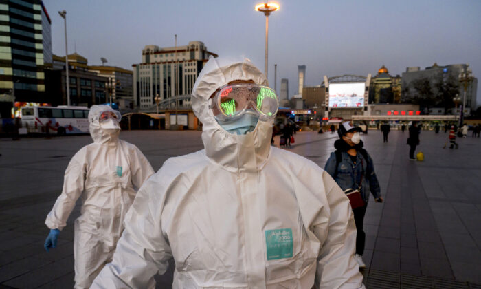 Les gens portent des masques et des costumes de protection à leur arrivée à la gare de Pékin le 13 mars 2020. (Kevin Frayer / Getty Images)