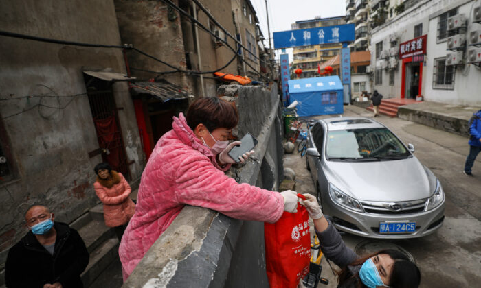Des habitants livrent des aliments par-dessus un mur qui ferme une rue à Wuhan, dans la province centrale de Hubei, en Chine, le 3 mars 2020. (STR/AFP via Getty Images)