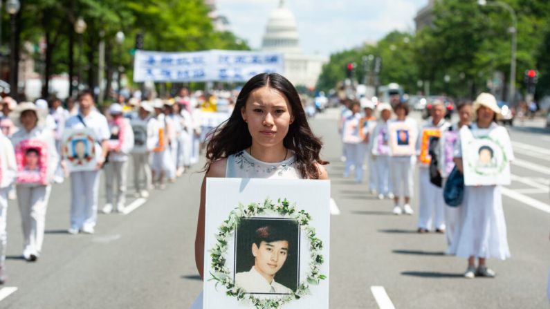Une femme tient une photo d'un homme tué au cours de la persécution du Falun Gong par le régime chinois, lors d'un défilé à Washington le 17 juillet 2014. (Larry Dye/The Epoch Times)