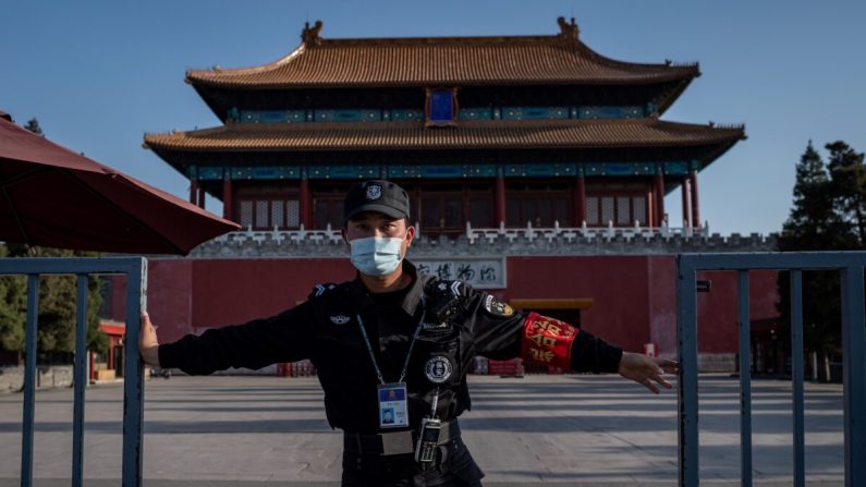 Un agent de sécurité portant un masque au milieu des inquiétudes suscitées par le coronavirus COVID-19 ferme une porte à l'extérieur de la ville interdite (arrière) de Pékin le 12 avril 2020. (Nicolas Asfouri/AFP via Getty Images)