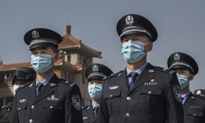 Des policiers chinois portant les masques de protection observent trois minutes de silence le jour de deuil national pour les victimes du COVID-19, à la gare de Pékin, le 4 avril 2020. (Kevin Frayer/Getty Images)