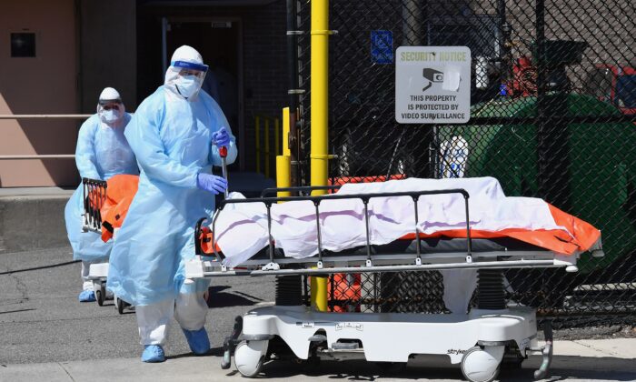 Le 2 avril 2020, le personnel médical déplace des corps du centre médical de Wyckoff Heights vers un camion réfrigéré à New York. (Angela Weiss/AFP/Getty Images)