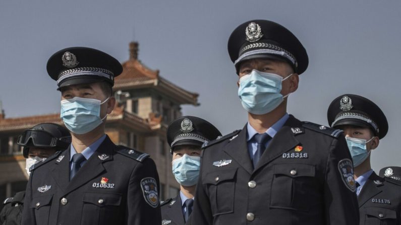 Des policiers chinois portent des masques de protection alors qu'ils observent trois minutes de silence pour marquer le jour de deuil national du pays pour le covid-19 à la gare de Pékin, en Chine, le 4 avril 2020. (Kevin Frayer/Getty Images)