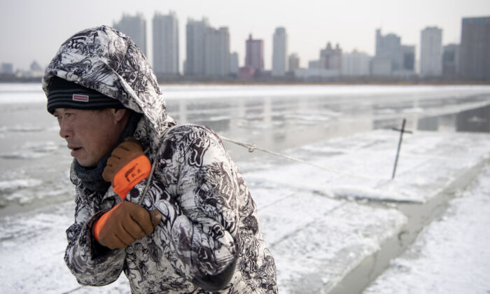 Un ouvrier traîne des blocs de glace sur la rivière Songhua gelée à Harbin, en Chine, le 11 décembre 2019. (NOEL CELIS/AFP via Getty Images)