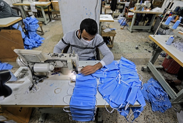 -Des travailleurs palestiniens fabriquent des combinaisons et des tenues de protection lors d'un atelier dans la ville de Gaza le 30 mars 2020 au milieu de la pandémie de coronavirus COVID-19. Photo de MAHMUD HAMS / AFP via Getty Images.