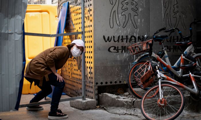Une femme portant un masque facial traverse une barricade à Wuhan, en Chine, le 7 avril 2020. (NOEL CELIS/AFP via Getty Images)