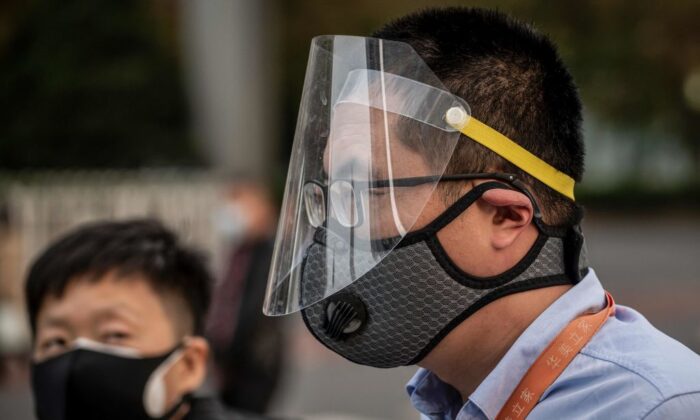 Un homme (d) portant un masque et un écran facial se rend à son travail dans une rue à l'heure de pointe à Pékin le 7 avril 2020. (Nicolas Asfouri/AFP via Getty Images)