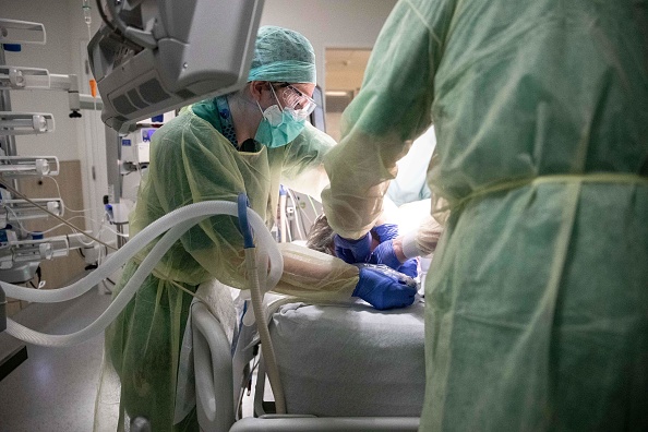 -Une infirmière, tourne la tête d'une patiente intubée le 11 avril 2020, dans l'unité de soins intensifs exclusivement réservée aux patients COVID-19 de l'hôpital Ixelles de Bruxelles. Photo par Aris Oikonomou / AFP via Getty Images.
