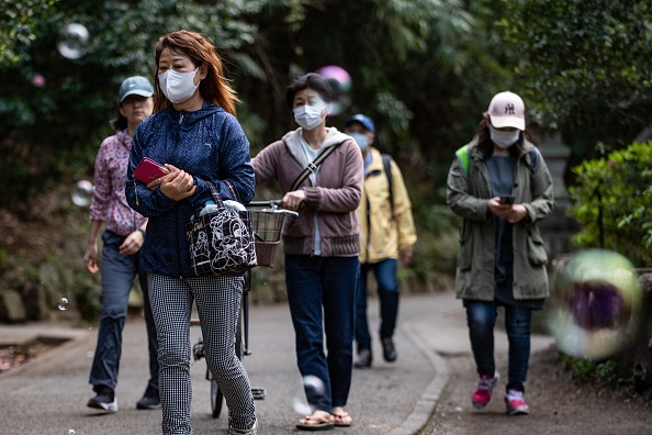 -Des bulles de savon passent devant des personnes portant des masques au parc Inokashira à Tokyo le 19 avril 2020. Photo de PHILIP FONG / AFP via Getty Images.