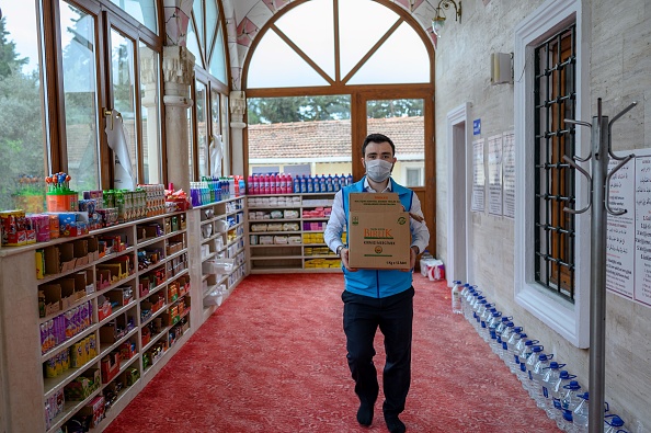 -Abdulsamet Cakir, 33 ans, imam de la mosquée Dedeman porte des cartons le 21 avril 2020. Les étagères réservées aux chaussures des fidèles musulmans sont remplies de nourriture ce qui rappelle un supermarché mais ils sont destinés aux nécessiteux durement touchés par la pandémie de coronavirus. Photo par Bulent Kilic / AFP via Getty Images.