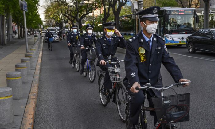 Des officiers chinois circulent ensemble à vélo dans une zone commerciale de Pékin, en Chine, le 22 avril 2020. (Kevin Frayer/Getty Images)