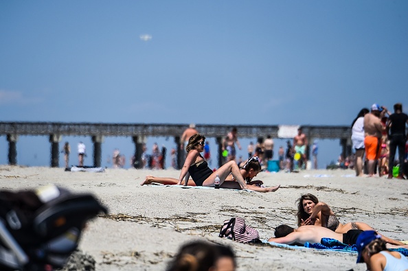 -Les gens se détendent sur la plage au milieu de la pandémie de coronavirus à Tybee Island, en Géorgie, le 25 avril 2020. Les nombreux habitants de la Géorgie cherchent refuge au soleil, dans le sable et les vagues des plages de l'Etat du sud. Photo de CHANDAN KHANNA / AFP via Getty Images.