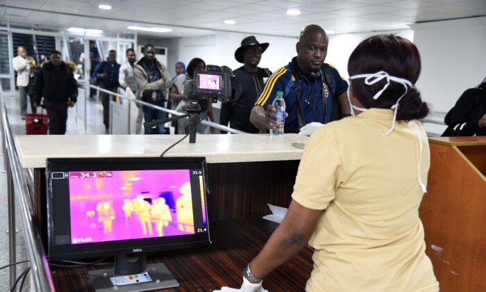 Un membre du personnel de la clinique Port Health Service se tient à côté d'un scanner thermique alors que les passagers arrivent à l'aéroport international Murtala Mohammed de Lagos, au Nigeria, le 27 janvier 2019. (PIUS UTOMI EKPEI/AFP via Getty Images)
