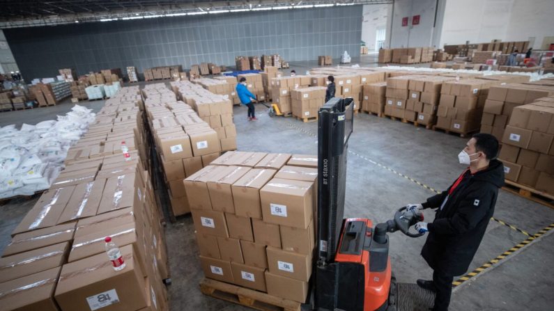 Le 4 février 2020, des membres du personnel et des bénévoles transfèrent du matériel médical dans un entrepôt d'un centre d'exposition à Wuhan, en Chine. (STR/AFP via Getty Images)