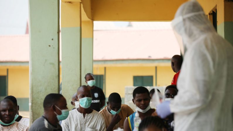 Des gens attendent alors que les professionnels de la santé se préparent à prélever des échantillons lors d'une campagne communautaire de dépistage du coronavirus à Abuja, au Nigeria, le 15 avril 2020. (Kola Sulaimon/AFP via Getty Images)