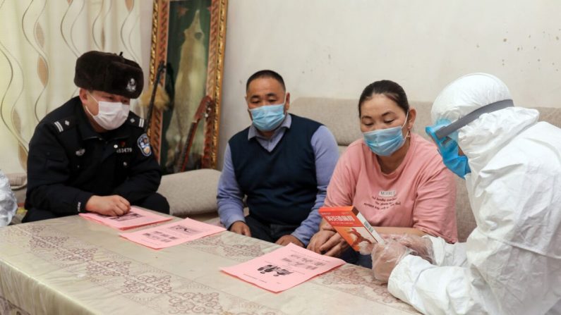 Des officiers de police (à gauche et à droite) rendent visite à des résidents qui vivent dans des zones reculées de l'Altaï, dans la région du Xinjiang en Chine, pour les informer sur le virus du PCC, le 19 février 2020. (STR/AFP via Getty Images)