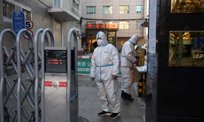 Les agents de sécurité portent des vêtements de protection lorsqu'ils attendent à l'entrée d'un restaurant à Pékin le 4 mars 2020. (Greg Baker/AFP via Getty Images) 