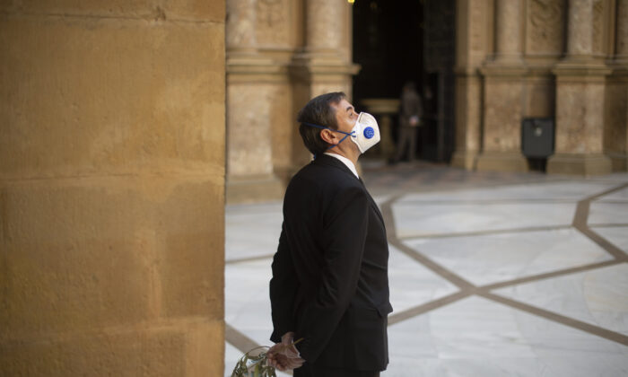 Un agent de sécurité portant un masque et des gants tient une branche d'olivier avant la célébration de la messe du dimanche des Rameaux à l'abbaye de Santa Maria de Montserrat à Monistrol de Montserrat le 5 avril 2020, (Josep Lago/AFP via Getty Images)