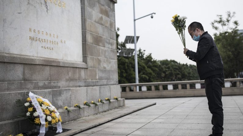 Un résident offre des fleurs aux martyrs morts dans la lutte contre l'épidémie du virus du PCC et aux compatriotes morts de la maladie à Wuhan, en Chine, le 4 avril 2020. (Getty Images)