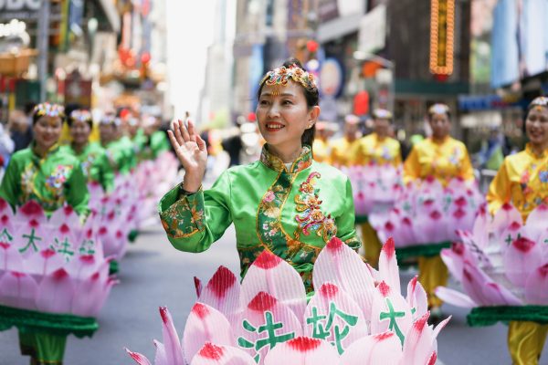 Une pratiquante de Falun Dafa en costume de fleur de lotus salue le public lors du défilé célébrant la Journée mondiale du Falun Dafa à Manhattan à New York, le 16 mai 2019. (Edward Dye/The Epoch Times)