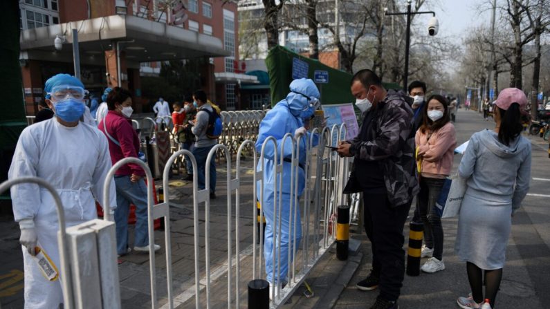 Le personnel hospitalier (à gauche) enregistre les patients sur le trottoir devant un hôpital pour enfants à Pékin le 31 mars 2020. (GREG BAKER/AFP via Getty Images)