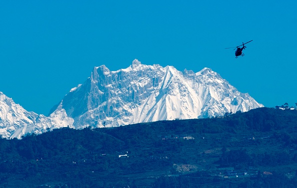 -Un hélicoptère vole avec une équipe de secours devant la chaîne de montagnes de l'Annapurna, à Pokhara, à environ 200 km à l'ouest de Katmandou le 22 janvier 2020. Ils ont retrouvé les corps des quatre randonneurs sud-coréens enterrés par une avalanche dans l'Himalaya. Photo de PRAKASH MATHEMA / AFP via Getty Images.