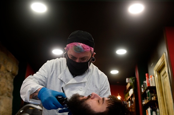 -Le coiffeur David Cores taille la barbe de son premier client après avoir rouvert son salon de coiffure à Pontevedra, le 4 mai 2020, pour la première fois. Les masques sont devenus obligatoires dans les transports publics aujourd'hui alors que l'Espagne a fait ses premiers pas vers une réouverture commerciale. Photo par MIGUEL RIOPA / AFP via Getty Images.