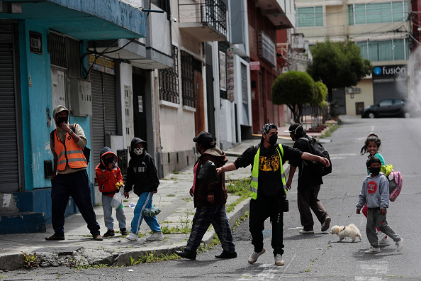 Des personnes avec des enfants marchent à la recherche de nourriture pendant le confinement ordonné par le gouvernement pour arrêter la propagation du Covid-19 le 4 mai 2020 à Quito, Équateur. Photo de Franklin Jacome / Getty Images.