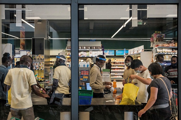 -Les clients font leurs courses aux caisses du supermarché à Adlife Plaza à Nairobi le 5 mai 2020. Les épiceries, ont également dû apporter des changements. Des masques sont requis, un contrôle thermique a lieu à l'entrée et les caddies sont régulièrement essuyés avec du désinfectant. Photo by KABIR DHANJI/AFP via Getty Image.