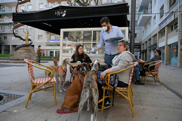 -Un serveur sert des clients dans un café de Tarragone le 11 mai 2020, alors que l'Espagne s'apprêtait à assouplir son verrouillage strict dans certaines régions. Photo par LLUIS GENE / AFP via Getty Images.
