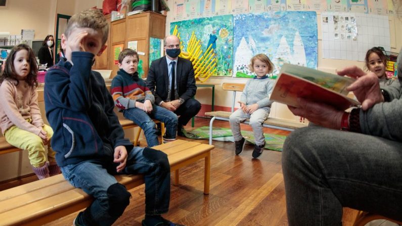 Le ministre français de l'Éducation et de la Jeunesse, Jean-Michel Blanquer, assis dans une classe et portant un masque, visite une école à Paris le 11 mai 2020 (Photo by JOEL SAGET/AFP via Getty Images)