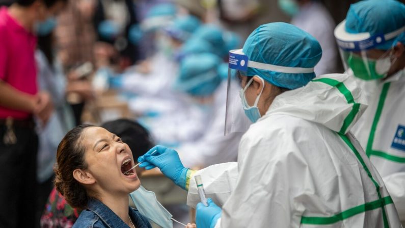 Un soignant prélève un échantillon par écouvillonnage sur une citoyenne pour le soumettre à un test de dépistage du virus du PCC à Wuhan, en Chine, le 15 mai 2020. (STR/AFP via Getty Images)