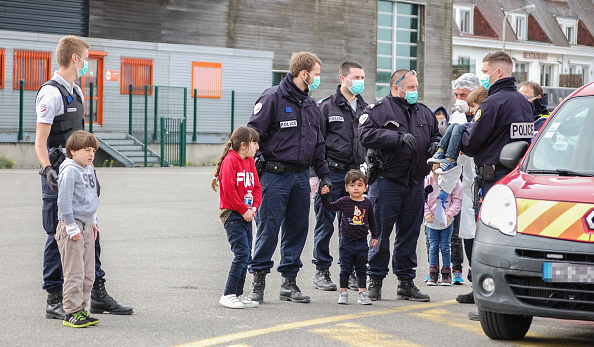 -Des gendarmes et des policiers français, portant des masques aident les migrants, dont cinq enfants et un bébé, qui ont tenté de rejoindre l'Angleterre en traversant la Manche et qui ont été secourus au large de la ville portuaire française de Calais le 16 mai 2020. Photo par BERNARD BARRON / AFP via Getty Images.