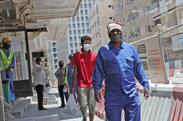 -Des travailleurs portent des masques de protection dans une rue de la capitale du Qatar, Doha, le 17 mai 2020. Les contrevenants aux nouvelles règles encourent jusqu'à trois ans de prison et des amendes pouvant atteindre 55 000 $. Photo par KARIM JAAFAR / AFP via Getty Images.