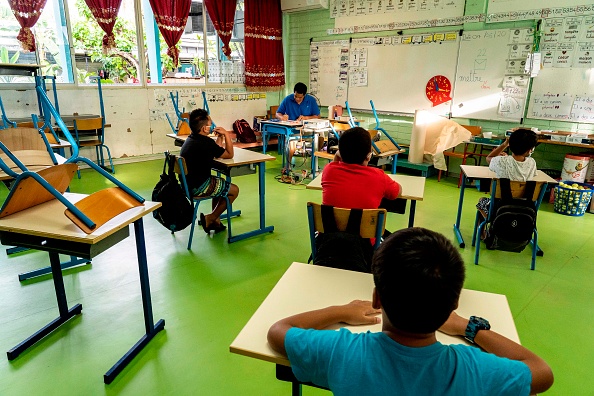 -Des écoliers portant des masques protecteurs assistent à une leçon dans une salle de classe de l'école primaire Taimoana à Papeete, sur l'île de Tahiti en Polynésie française, le 18 mai 2020. Photo de Suliane FAVENNEC / AFP via Getty Images.