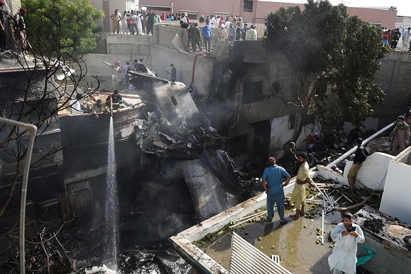 Les pompiers pulvérisent de l'eau sur l'épave d'un avion de la Pakistan International Airlines qui s'est écrasé dans un quartier résidentiel de Karachi le 22 mai 2020. (Photo : RIZWAN TABASSUM/AFP via Getty Images)