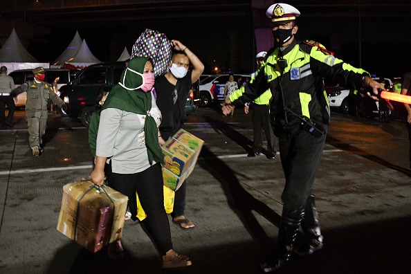 -Les personnes qui se rendent dans leur ville natale pour les célébrations de l'Aïd al-Fitr marquant la fin du mois sacré musulman du Ramadan, sont invitées par la police à retourner à Jakarta en raison de l'interdiction de voyager pour empêcher la propagation du coronavirus COVID-19, à Cikarang, le 23 mai 2020. Photo par DASRIL ROSZANDI / AFP via Getty Images.