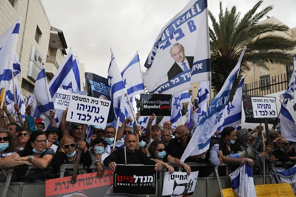 -Les partisans israéliens du Premier ministre Benjamin Netanyahu tiennent des drapeaux et des pancartes lors d'un rassemblement devant le tribunal de district de Jérusalem le 24 mai 2020. Photo de MENAHEM KAHANA / AFP via Getty Images.