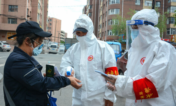 Le 25 mai 2020, le personnel vérifie la température corporelle d'un résident à l'extérieur d'un complexe résidentiel de la ville de Jilin, en Chine. (STR/AFP via Getty Images)