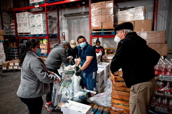 -Le pasteur luthérien Fabian Arias parle avec des bénévoles alors qu'ils préparent et chargent des dons de livraison de nourriture le 19 mai 2020 dans le quartier du Bronx à New York. Photo par JOHANNES EISELE / AFP via Getty Images.