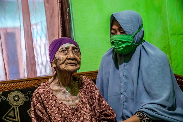 -Kamtim, 100 ans, est assise dans son salon avec sa belle-fille Siti Aminah à Surabaya, le 31 mai 2020, après être sortie de l’hôpital après un mois de traitement du COVID. Photo de Juni Kriswanto / AFP via Getty Images.