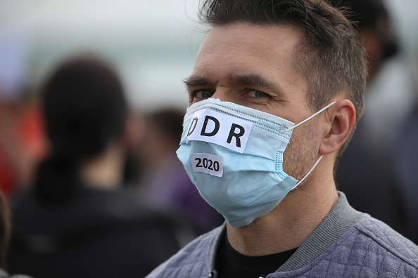 Un manifestant, portant un masque facial avec un signe "DDR 2020" manifeste contre les mesures  de confinement et la politique du gouvernement  pendant la crise des coronavirus le 23 mai 2020 à Cologne, en Allemagne. (Photo : Andreas Rentz/Getty Images)