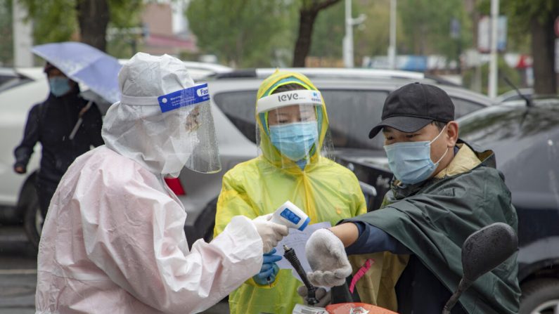 Des volontaires vérifient la température corporelle d'un habitant à l'entrée d'un complexe résidentiel de la ville de Jilin, en Chine, le 22 mai 2020. (STR/AFP via Getty Images)