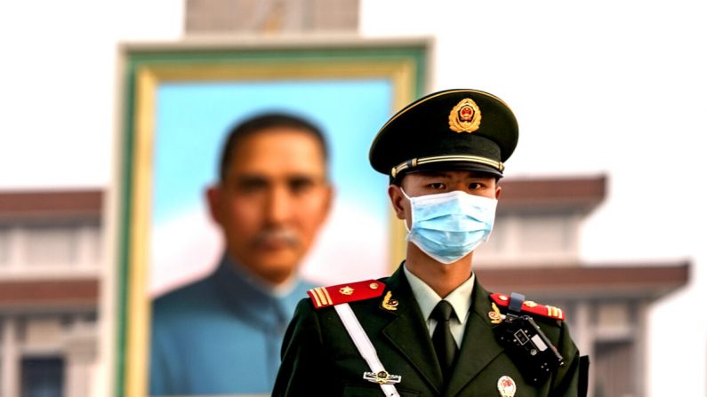 Un policier chinois portant un masque de protection marche devant le portrait du fondateur nationaliste Sun Yat-sen sur la place Tiananmen à Pékin, en Chine, le 28 avril 2020. (Lintao Zhang/Getty Images)