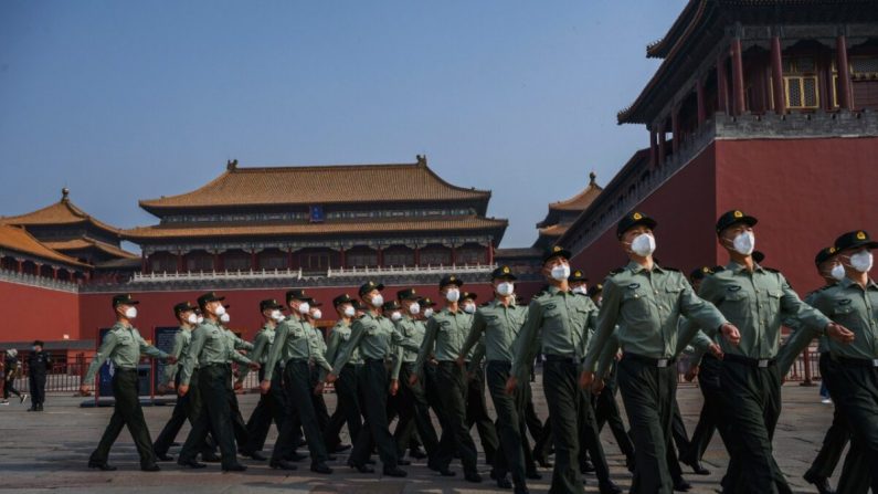 La police paramilitaire chinoise porte des masques de protection lorsqu'elle passe devant l'entrée de la Cité interdite, qui a réouvert ses portes à un nombre limité de visiteurs pour les vacances de printemps, le 2 mai 2020 à Pékin, en Chine. (Kevin Frayer/Getty Images)