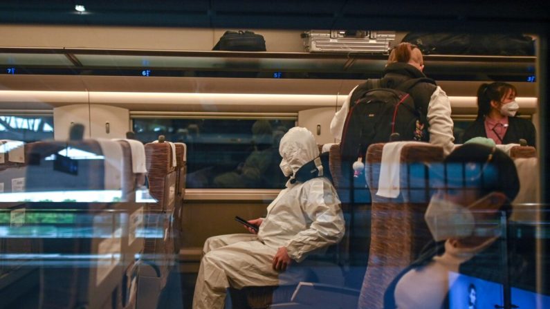 Un homme portant une combinaison de protection monte dans un train en direction de Shanghai à la gare de Wuhan, dans la province centrale de Hubei, en Chine, le 21 avril 2020. (HECTOR RETAMAL/AFP via Getty Images)