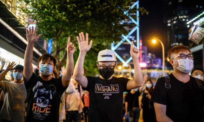 Des manifestants pro-démocratie brandissent le slogan « cinq exigences et pas une de moins » lors d'une veillée devant le centre commercial Pacific Place dans le quartier de l'Amirauté à Hong Kong le 15 mai 2020, pour marquer l'anniversaire des 11 mois depuis qu'un homme est tombé d'un échafaudage, lors d'une manifestation contre le projet de loi d'extradition du gouvernement de Hong Kong l'année dernière. (Anthony Wallance/AFP via Getty Images)